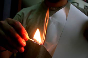 Chico quemando un papel con una cerilla