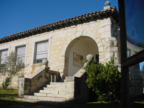Fachada de piedra con arco y escalera en Cabanillas de la Sierra