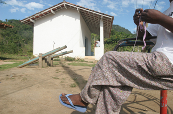 Mujer tejiendo delante de una casa en Quilombo, Sao Paulo, Brasi