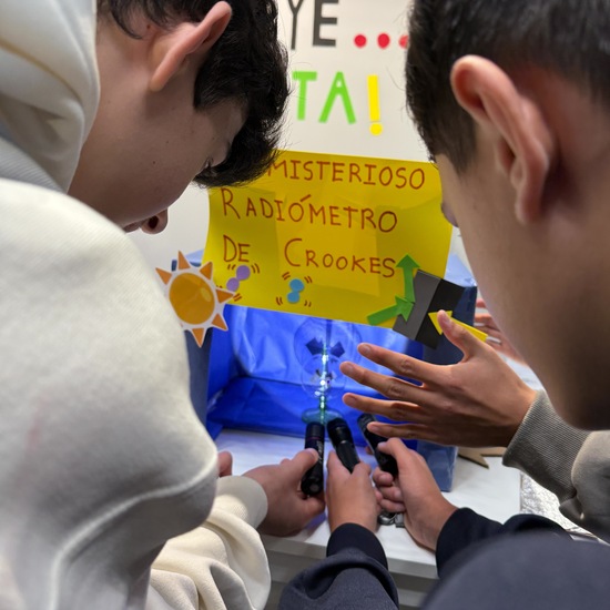 Un par de adolescentes realiza un experimento con el radiómetro de Crookes en el stand del IES Enrique Tierno Galván de Parla
