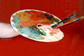 Persona agarrando una paleta y unos pinceles