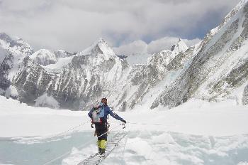 Escalador cruzando una grieta en un glaciar con una escalera
