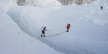 Escalador cruzando una grieta en un glaciar con una escalera