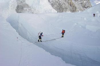 Escalador cruzando una grieta en un glaciar con una escalera