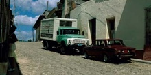 Coche y furgoneta aparcados delante de una casa, Cuba
