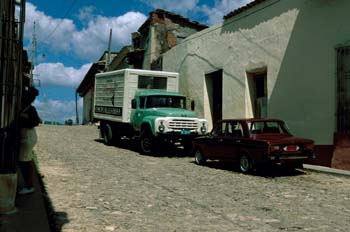 Coche y furgoneta aparcados delante de una casa, Cuba