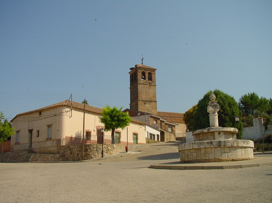 Plaza con fuente e iglesia al fondo en Ribatejada