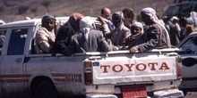 Grupo de hombres en una furgoneta abierta, llegando a un mercado