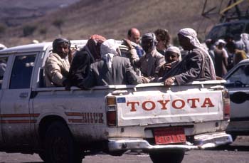 Grupo de hombres en una furgoneta abierta, llegando a un mercado