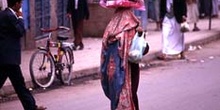 Mujer con bulto sobre la cabeza en una calle de Sanaa, Yemen
