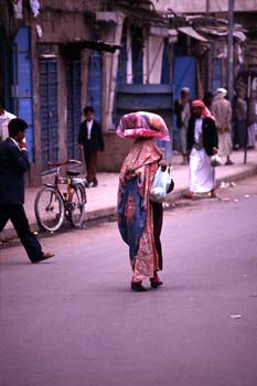 Mujer con bulto sobre la cabeza en una calle de Sanaa, Yemen
