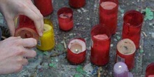 Persona encendiendo un cirio en recuerdo a las víctimas del Aten