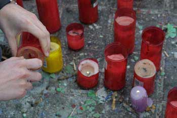 Persona encendiendo un cirio en recuerdo a las víctimas del Aten