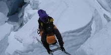 Escalador cruzando una grieta en un glaciar con una escalera