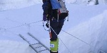 Escalador cruzando una grieta en un glaciar con una escalera