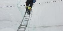 Escalador subiendo pared de un glaciar con una escalera
