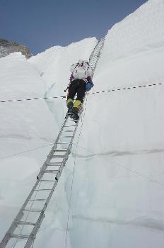 Escalador subiendo pared de un glaciar con una escalera