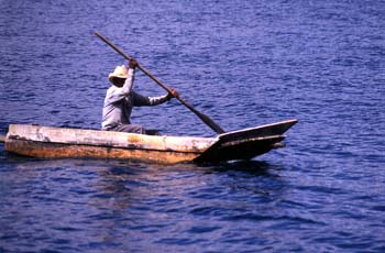 Hombre remando en una barca de fondo plano en el lago Atitlán, G