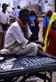 Cambista ofreciendo moneda fraccionaria para limosna, Pushkar, I